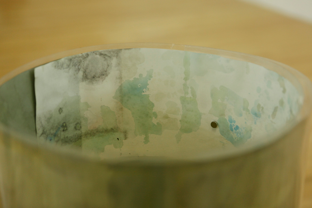 Detail of how the tube like sculpture containing drawings is looking from inside, another magnet and various layers of watercolor drawings are visible