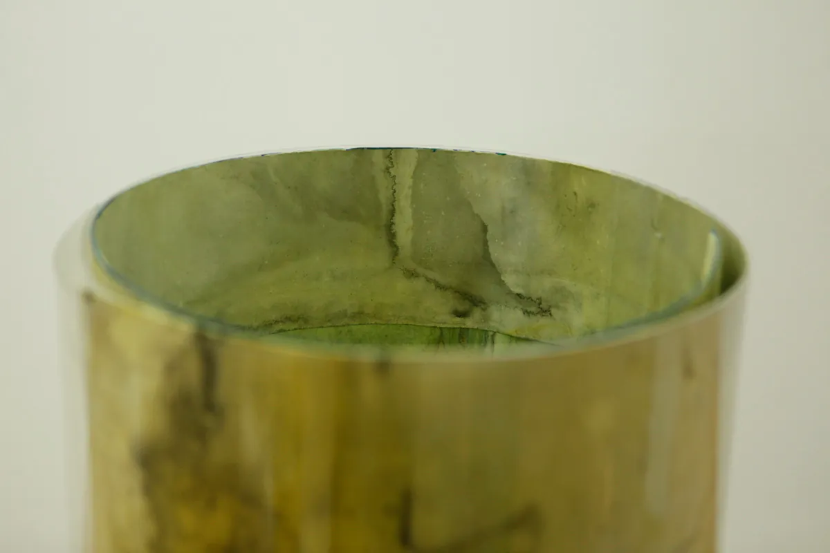 Detail of how the tube like sculpture containing drawings is looking from inside, a watercolor drawing is visible inside, a bit yellow-green, the only tube that had only one drawing in itself