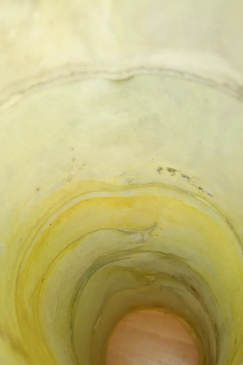 Detail of how the tube like sculpture containing drawings is looking from inside, a yellowish tube like void is visible reaching the floor