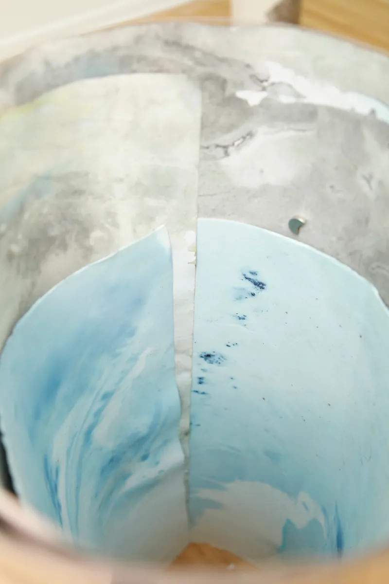 Detail of how the tube like sculpture containing drawings is looking from inside, a magnet and various layers of watercolor drawings are visible