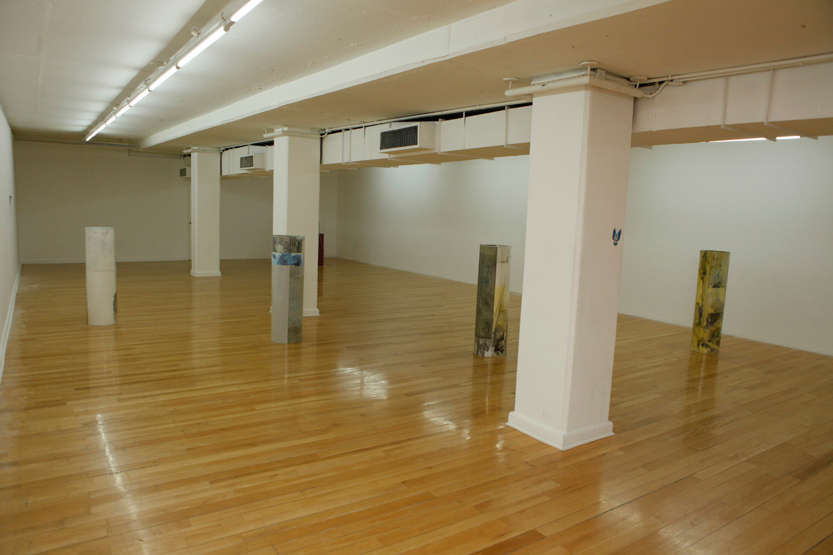 Sculpture installation where a series of drawings are rolled up between two polycarbonate sheets, creating a tube like shape standing vertically and aligned in a line, crossing tranversally the gallerys space